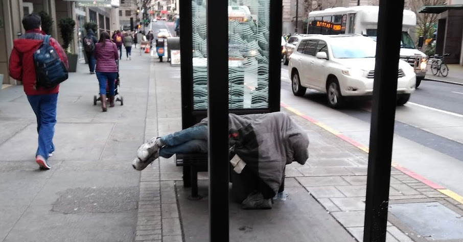 Homeless man on uncomfortable bench